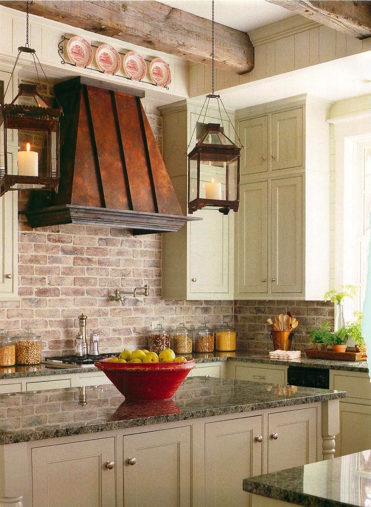 The exposed brick in this kitchen with the copper, textured countertops, wood beams, and pops of cream are lovely.