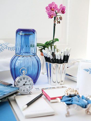 Desk space for a guest - orchid, blue water carafe, alarm clock, sharpened pencils, paper - Carolyne Roehm in Veranda: 