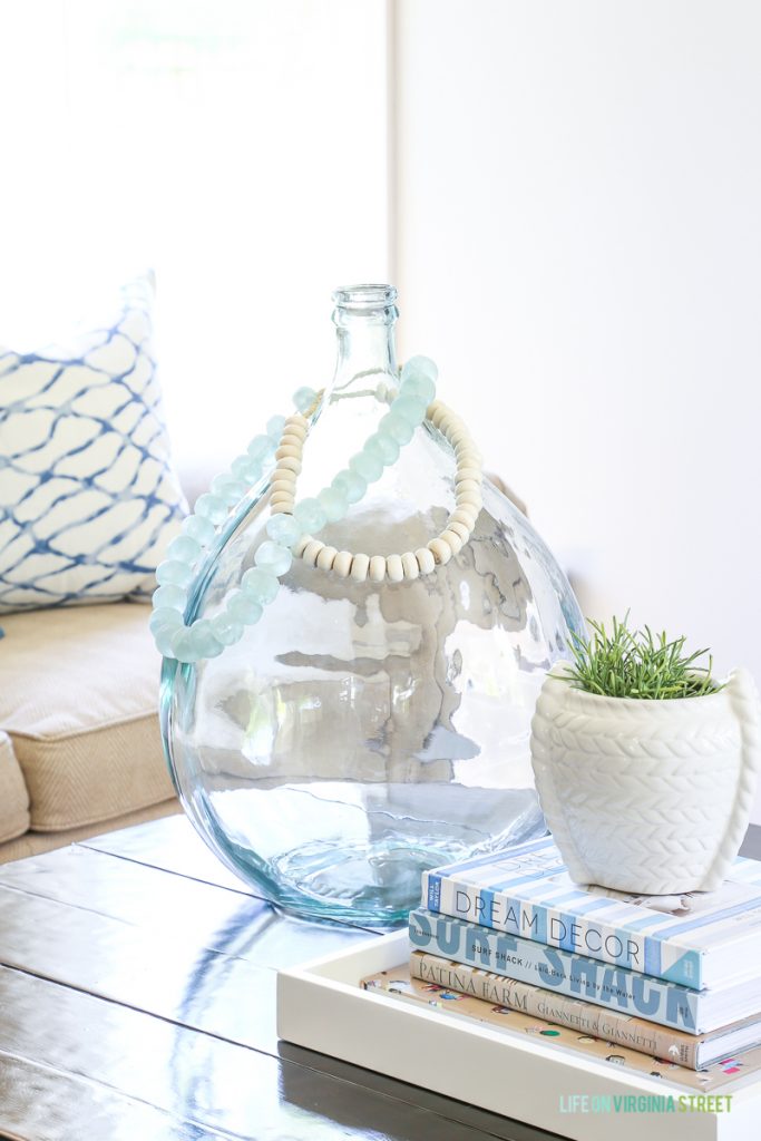 Sea glass beads on a large demijohn vase. Love this coastal style vignette that's perfect for a blue and white living room!
